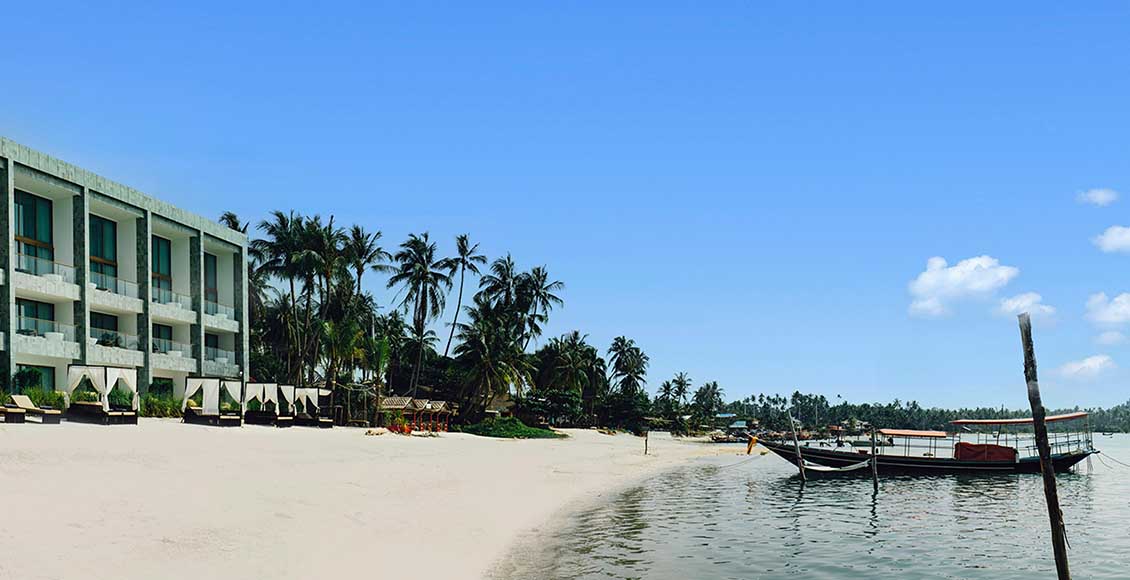 The Beach Samui shoreline with longtail boats at the water's edge